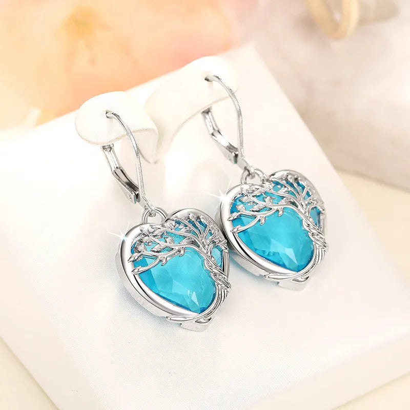 Blue crystal heart-shaped dangling earrings from Corporación Turística, featuring elegant, shimmering pendant design.