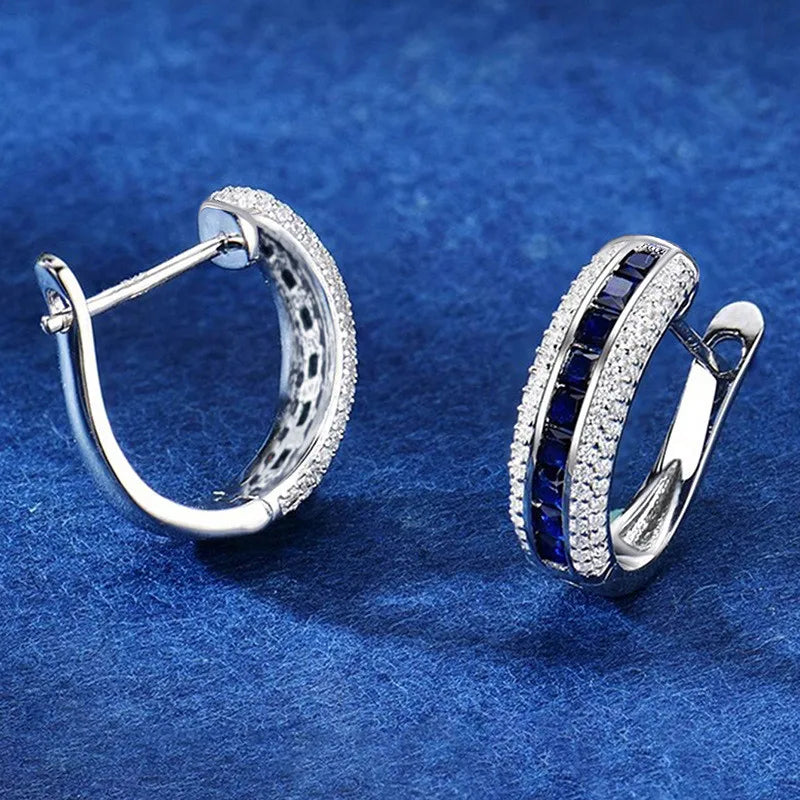 Sterling silver hoop earrings with cubic zirconia from Corporación Turística, showcasing shiny, elegant jewelry with sparkling stones.