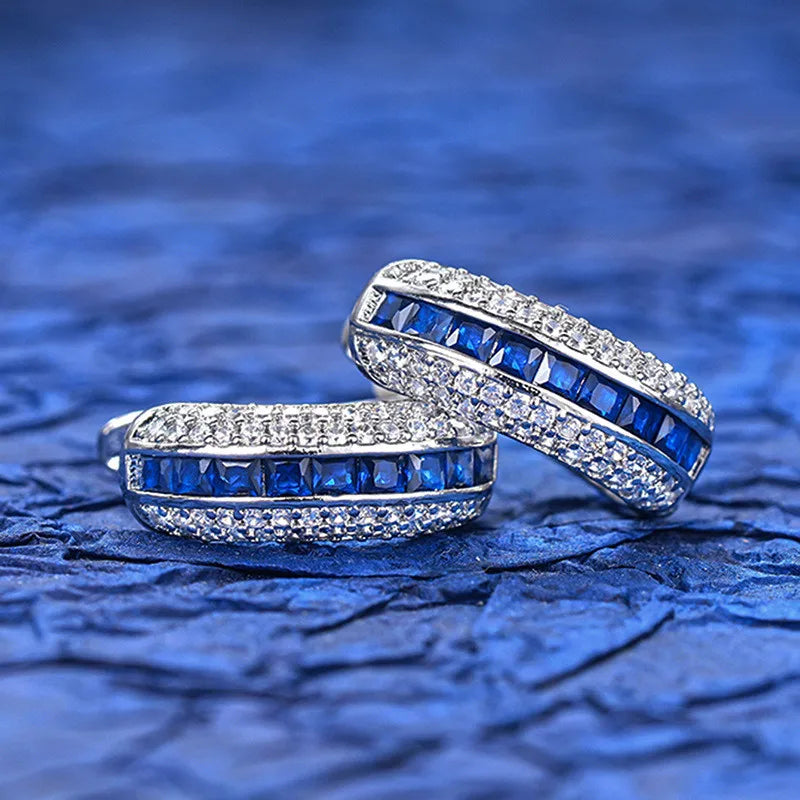 Sterling silver hoop earrings with cubic zirconia by Corporación Turística, showcasing shiny round design and sparkling stones.