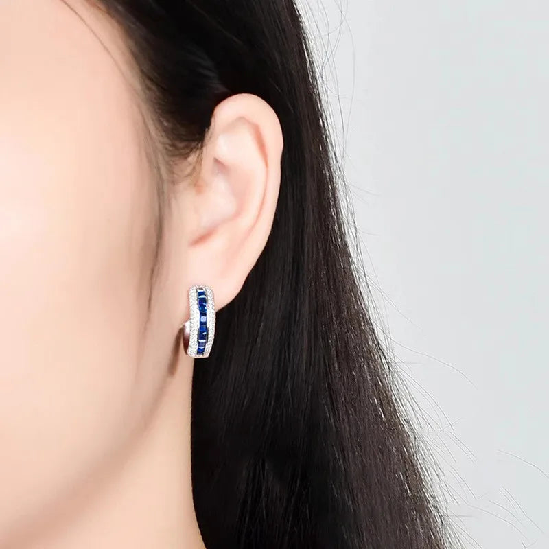 Sterling silver hoop earrings with cubic zirconia by Corporación Turística, showcasing shiny, elegant jewelry with sparkling stones.