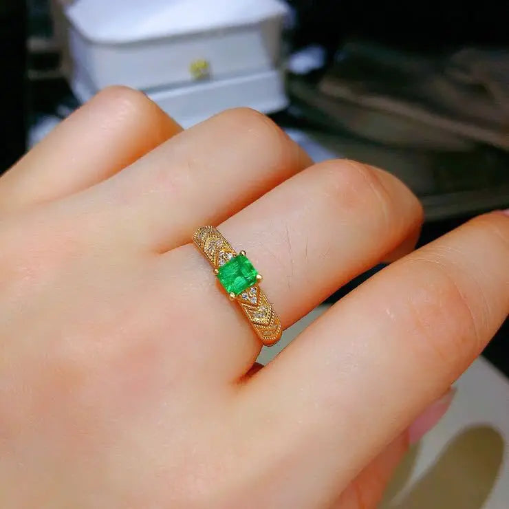 18K gold women's ring with a natural emerald gemstone, featuring a detailed gold band and elegant design.