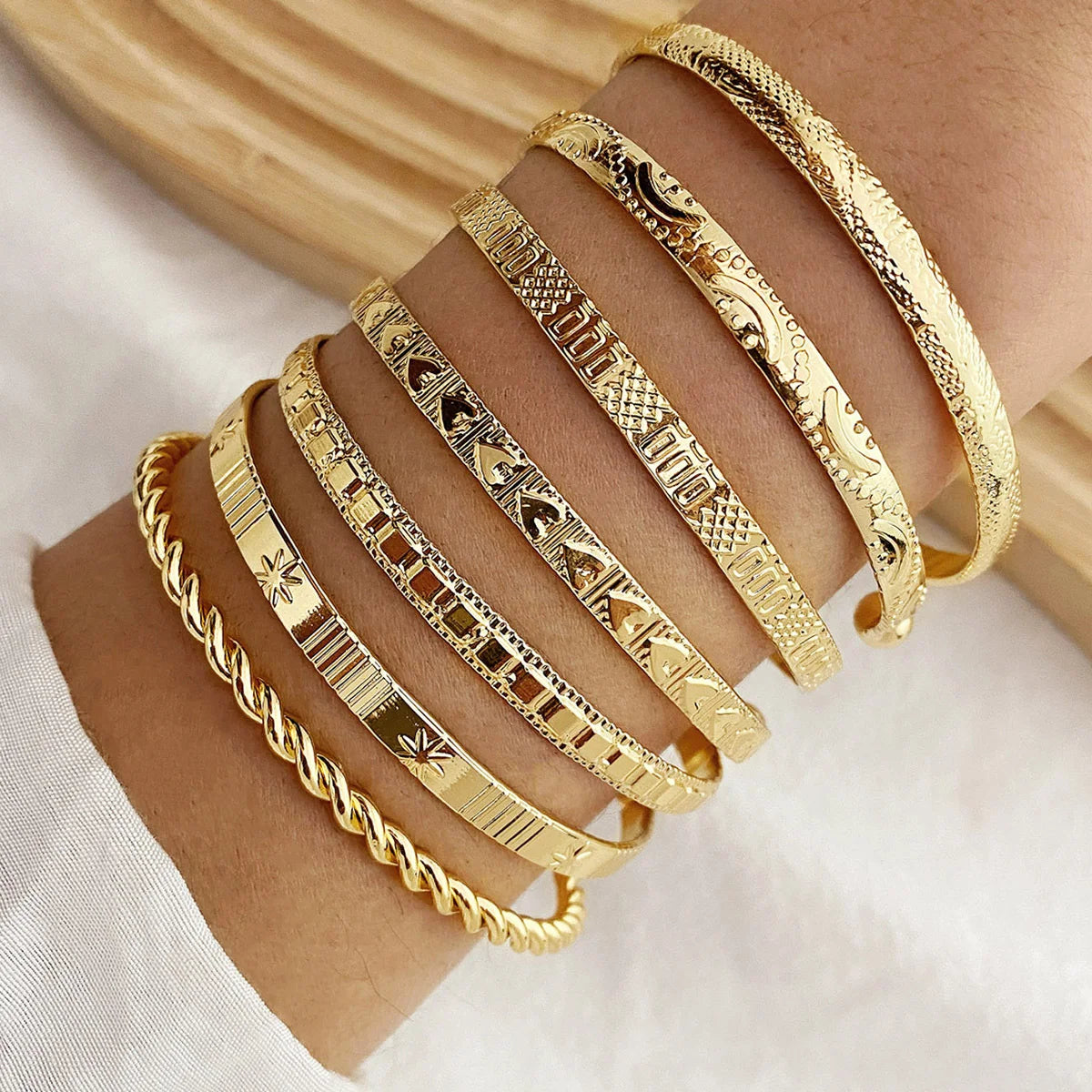 Set of seven gold-colored punk bracelets for women featuring bold metal designs and adjustable bands.
