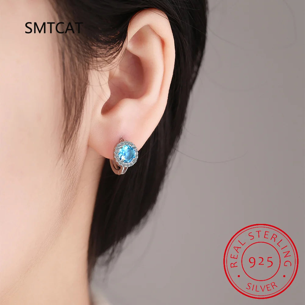 Sterling silver 925 blue sapphire hoop earrings with elegant design, featuring vibrant blue gemstones and polished silver finish.