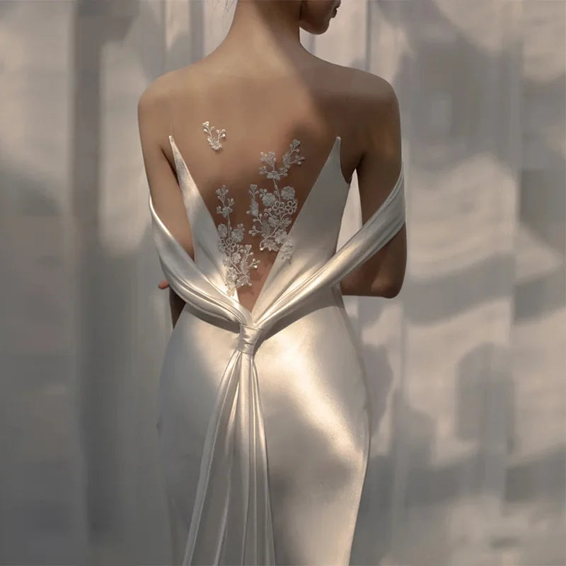 Lightweight backless wedding dress by Corporación Turística, elegant white bridal gown with a flowing design and delicate details.