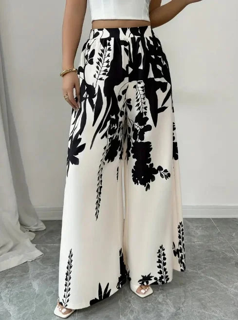 Wide-leg satin floral pants in white, featuring a soft, silky fabric and vibrant floral print from Corporación Turística.