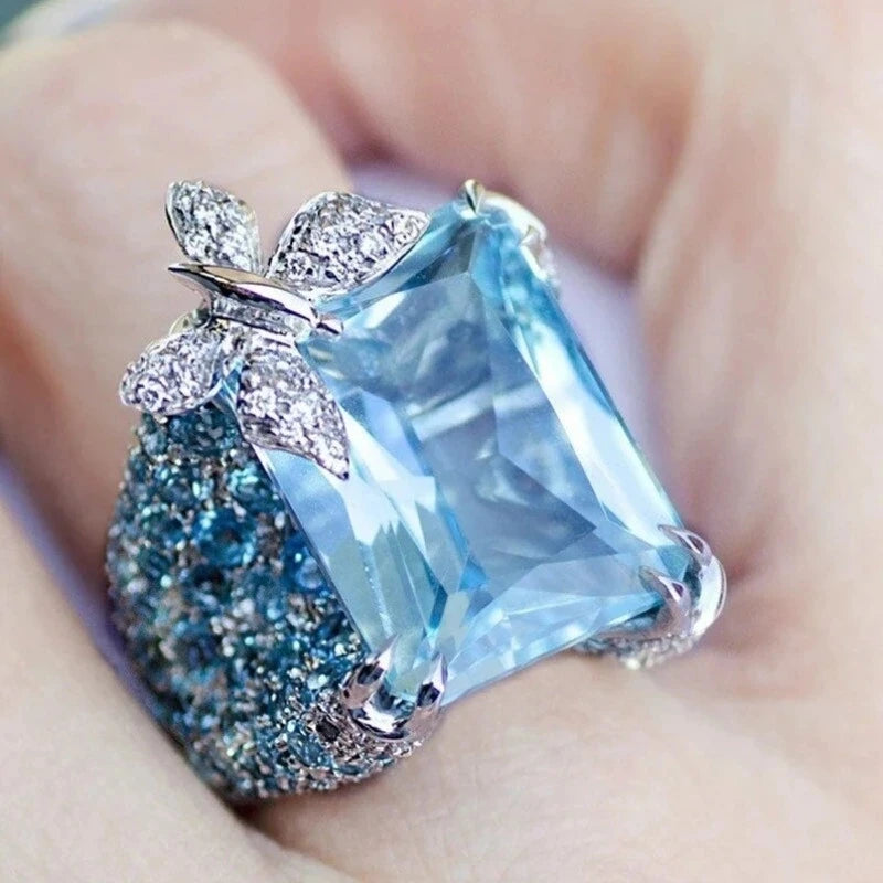 Elegant blue topaz cocktail ring by Butterfly, featuring a detailed butterfly design and sterling silver band.