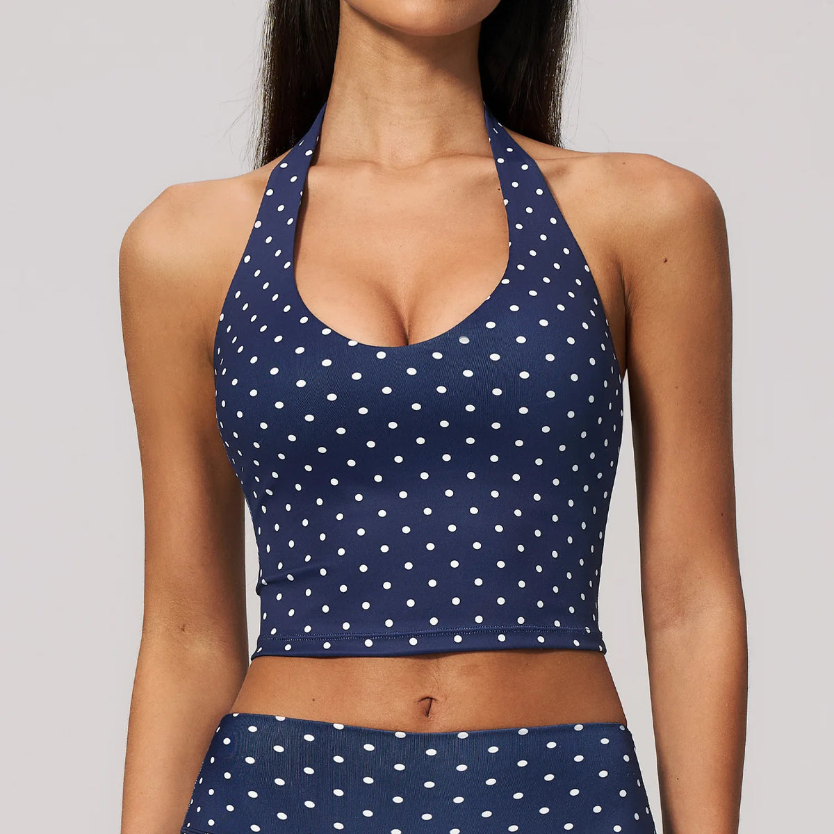 Blue women's yoga sports top with white polka dot print from Corporación Turística, stretchy and comfortable athletic wear for active women.