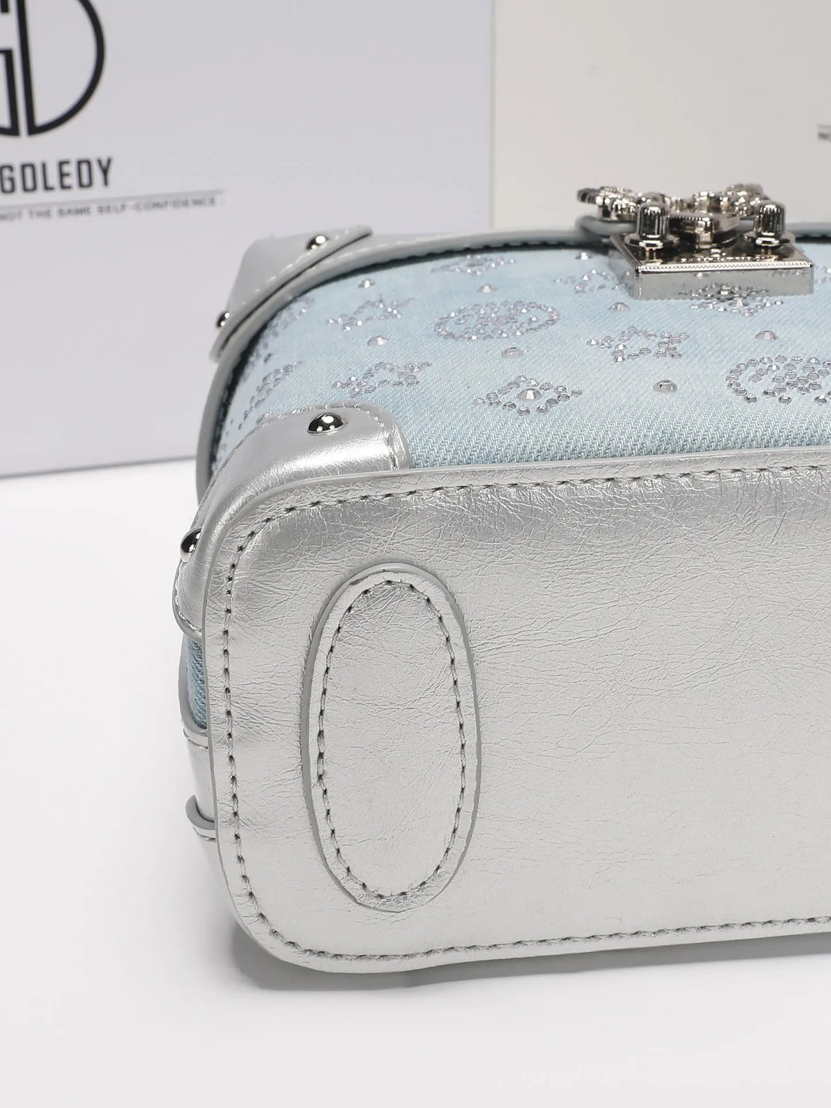 Luxury blue handbag from Corporación Turística featuring a delicate pendant, stylish and popular for elegant occasions.