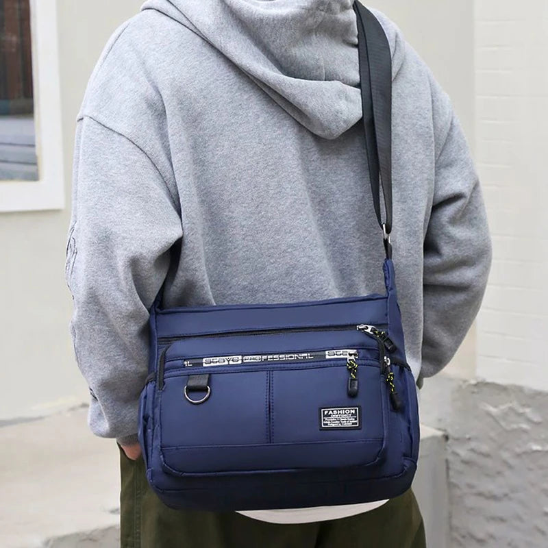 Black nylon men's shoulder bag, multi-layer design, ideal for travel and business, by Corporación Turística.