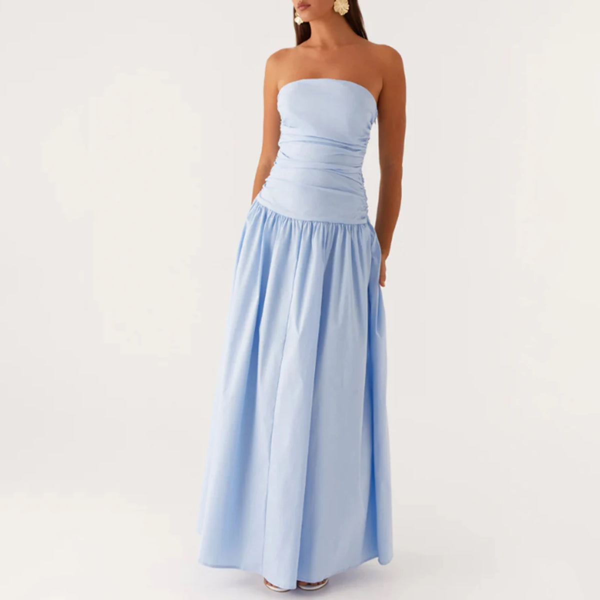 Elegant long beige strapless dress for women, by Corporación Turística, displayed on a model showing its flowing fabric and stylish design.