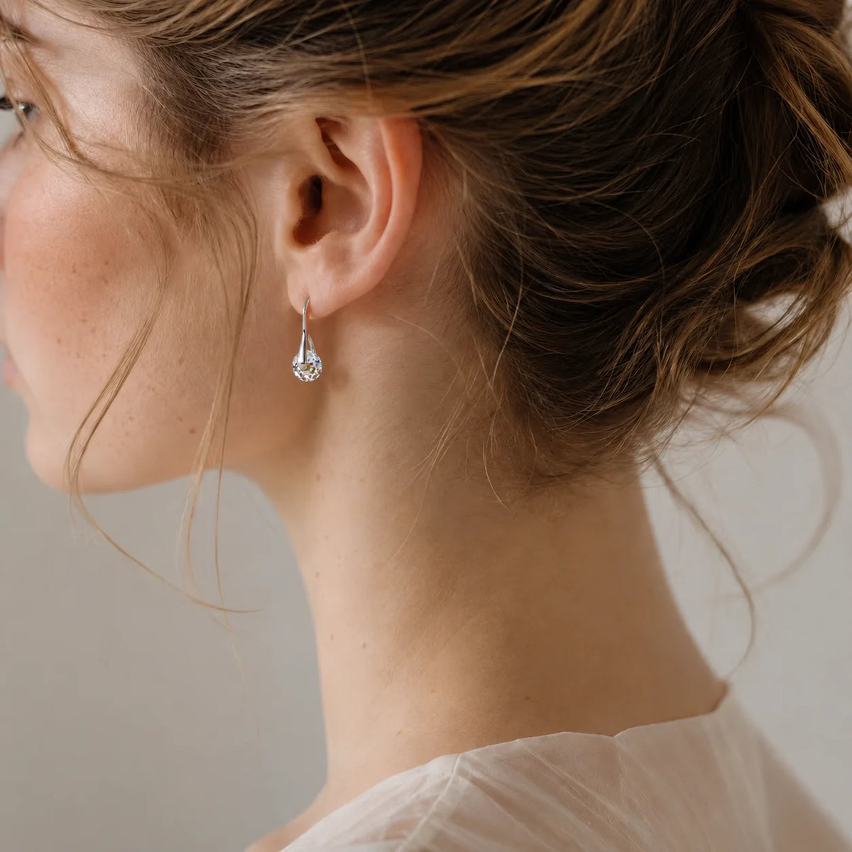 Elegant dangling earrings with round crystal beads from Corporación Turística, showcasing shimmering crystal details and silver hooks.