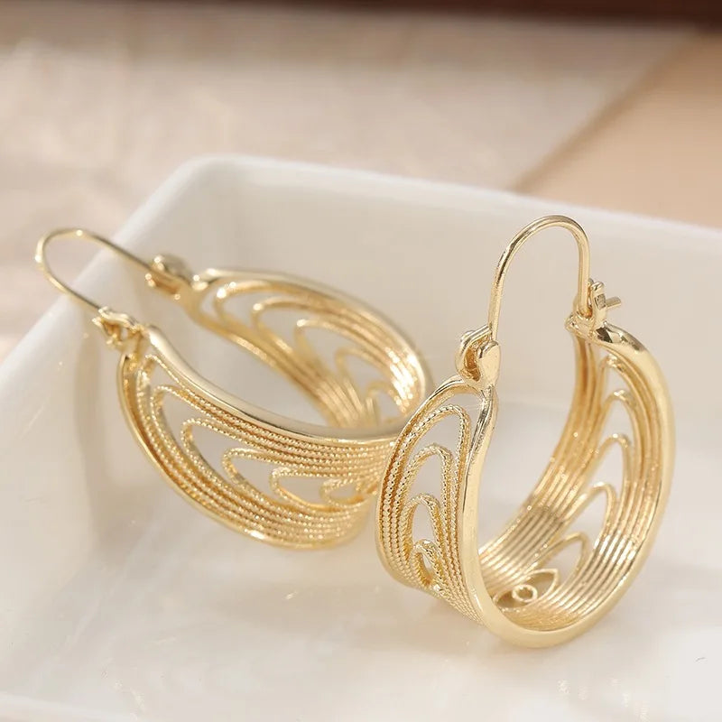 Gold pendant earrings for women featuring intricate patterns, stylish and elegant jewelry by Corporación Turística.