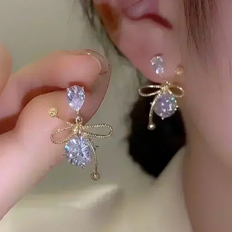 Exquisitos pendientes colgantes de cristal en forma de gota, en color blanco, de la marca Corporación Turística.