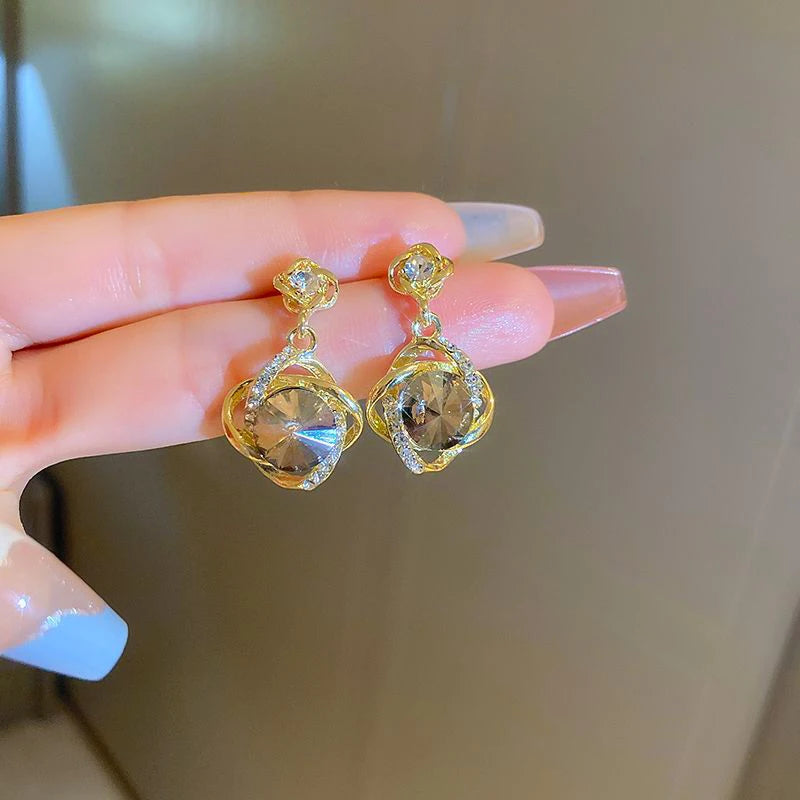Elegant gold earrings with round crystal pendants wrapped in decorative metal, showcasing intricate craftsmanship.