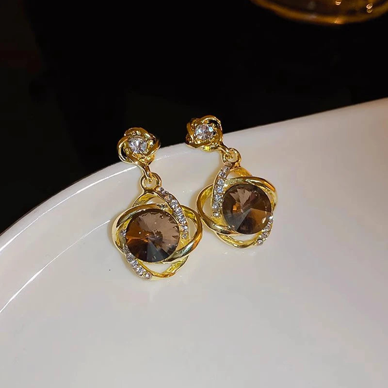 Elegant earrings with round crystal pendants wrapped in decorative wire, jewelry by Corporación Turística.
