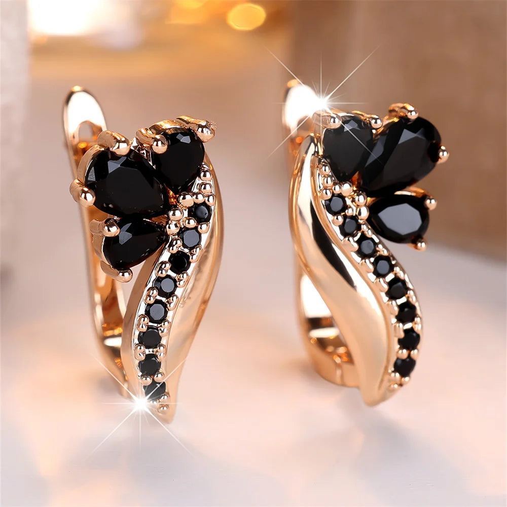 Gold and black hoop earrings with teardrop-shaped crystal water stone pendants, handcrafted jewelry by Corporación Turística.