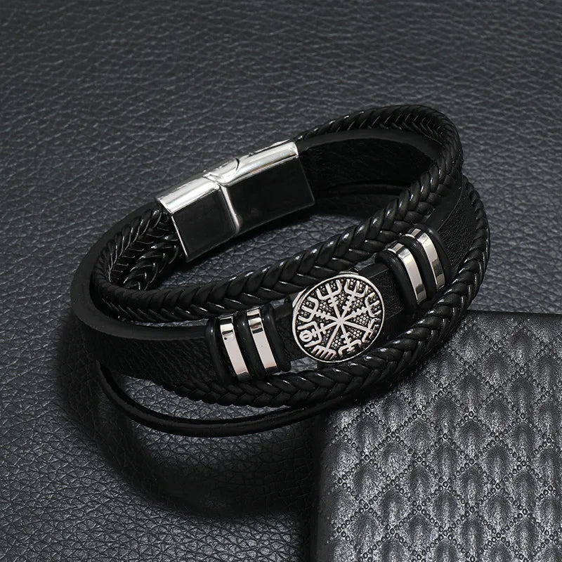 Black leather men's bracelet with multi-layer braided design, featuring a compass and evil eye charms, from Corporación Turística.