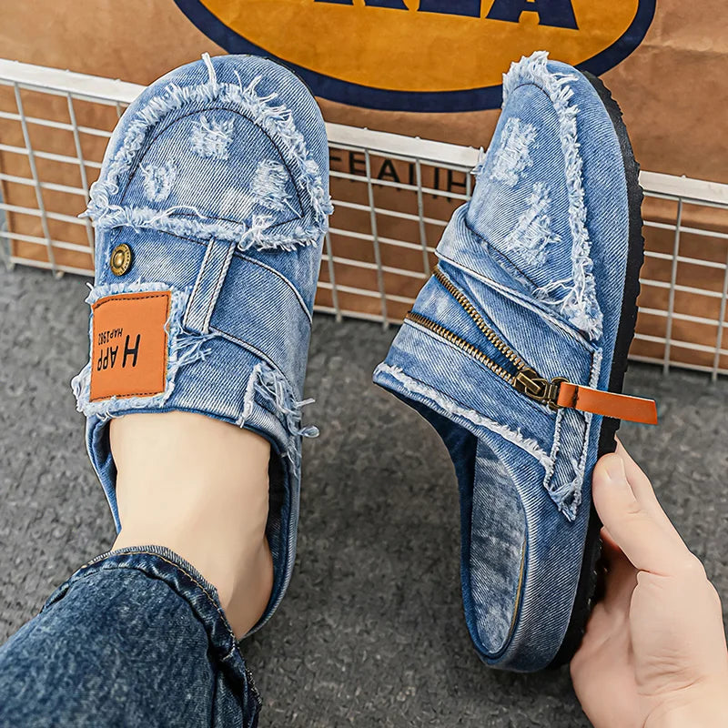 Light blue denim mules with frayed edges from Corporación Turística, showing the textured fabric and stylish slip-on design.