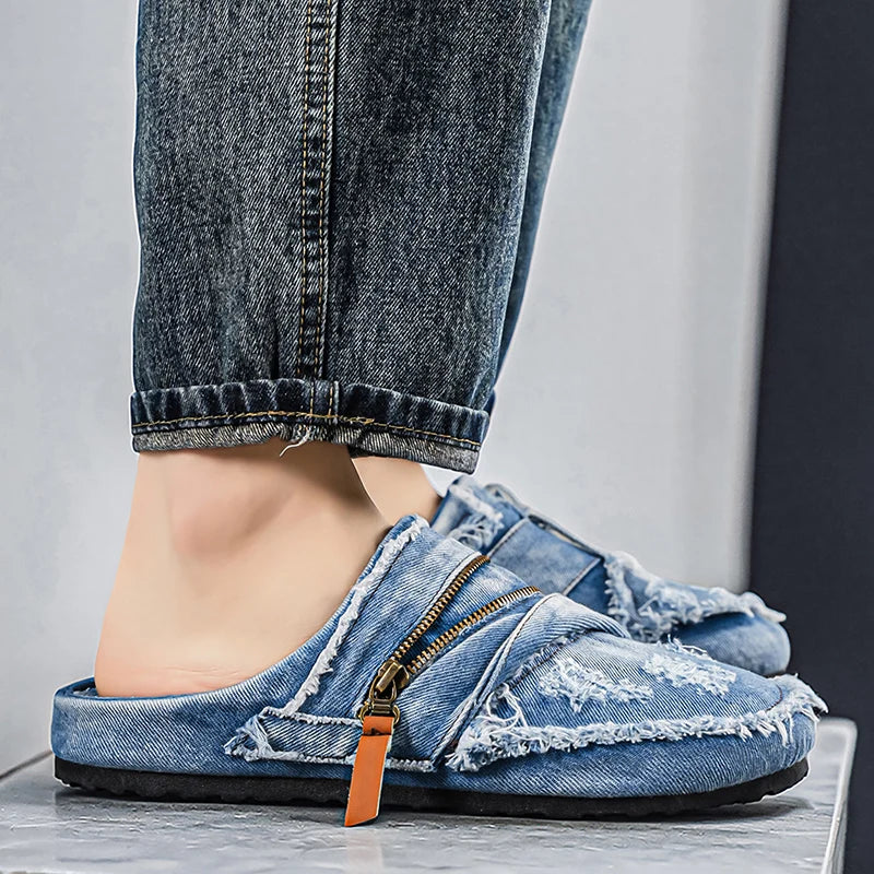 Light blue denim mules with frayed edges from Corporación Turística, featuring a casual slip-on style and distressed finish.