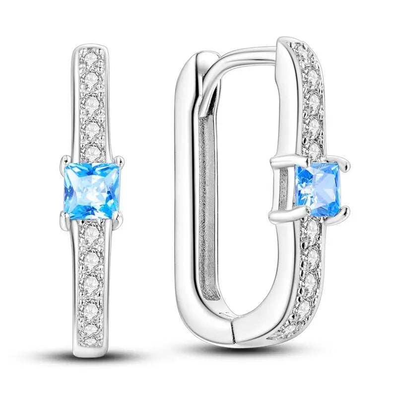 Sterling silver Orstarry earrings with blue cubic zirconia from Corporación Turística, featuring a polished hoop design.