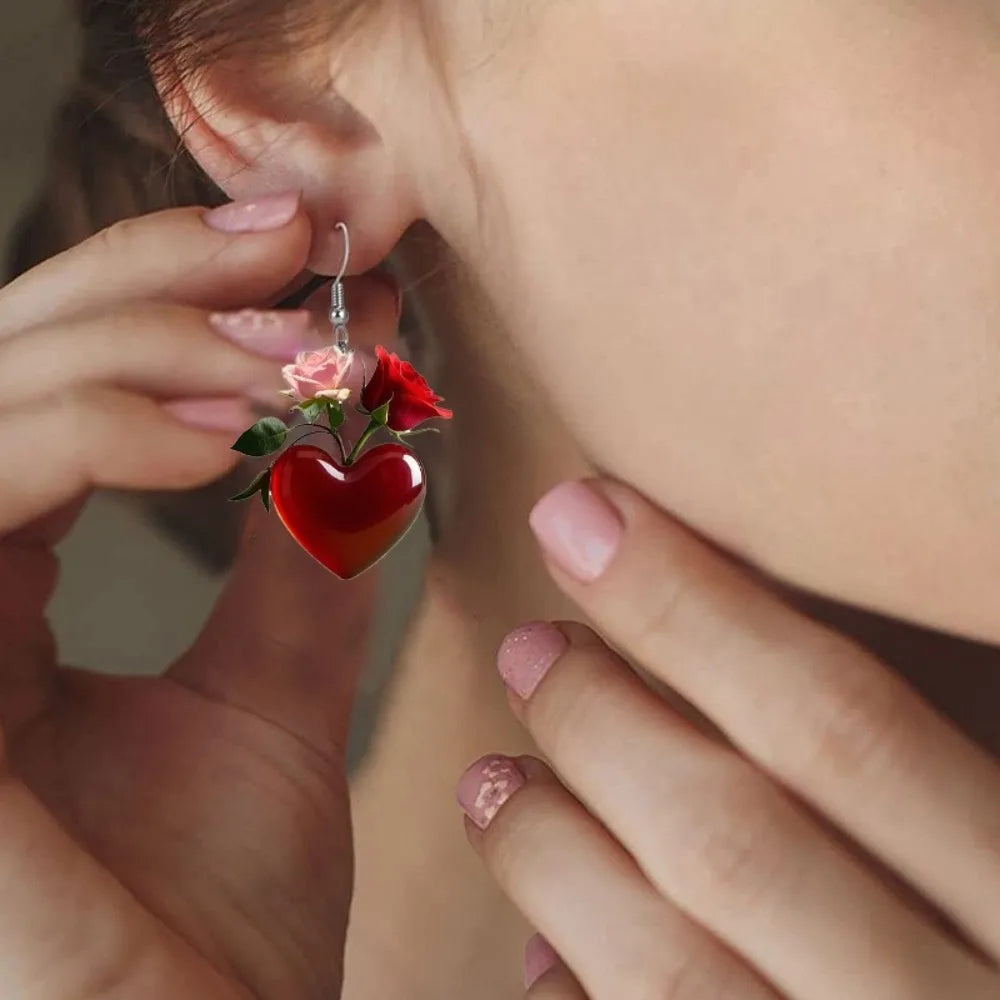Acrylic heart-shaped dangling earrings from Corporación Turística featuring vibrant red color and modern jewelry design.