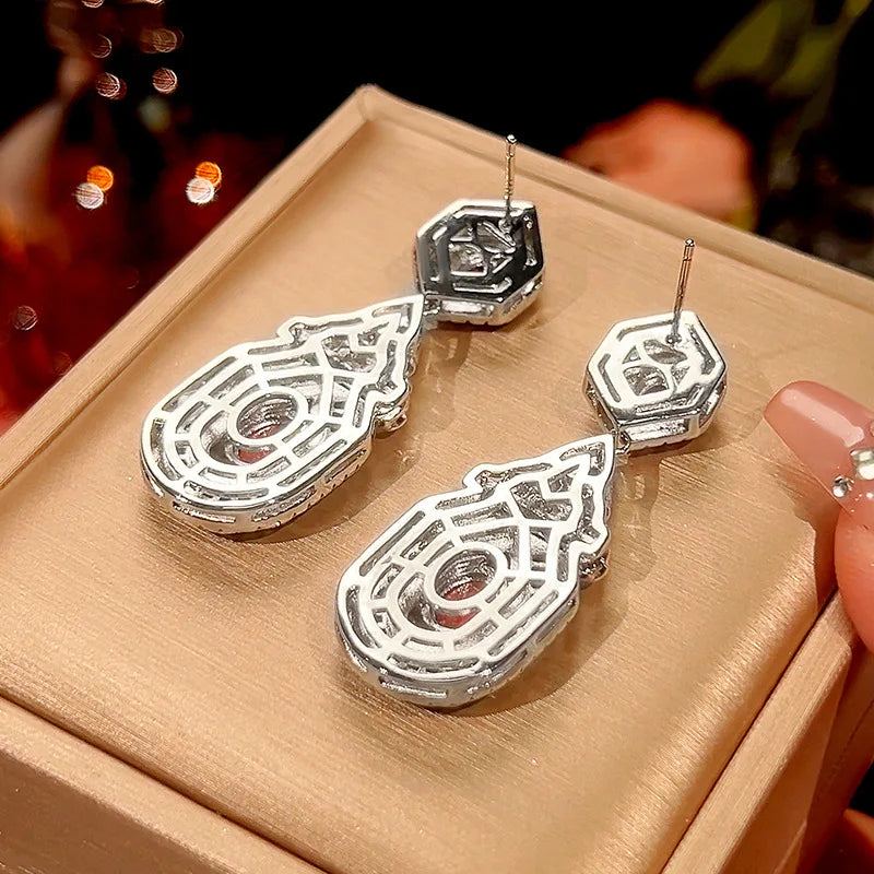 Vintage style dangling earrings with red stud accents by Corporación Turística, featuring a fashionable pendant design.