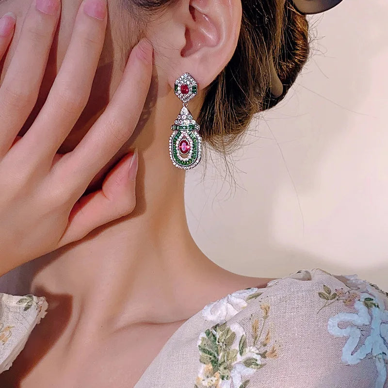 Vintage style dangling earrings from Corporación Turística featuring red stud accents and fashionable design.