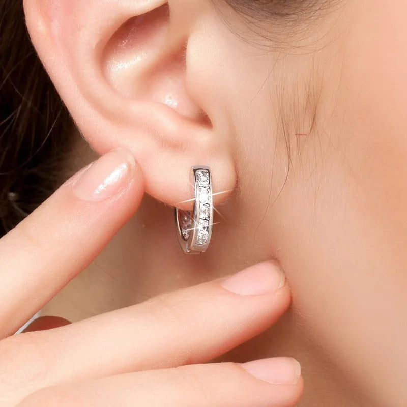 Sterling silver earrings with sparkling cubic zirconia stones, showcasing elegant, shiny jewelry by Corporación Turística.