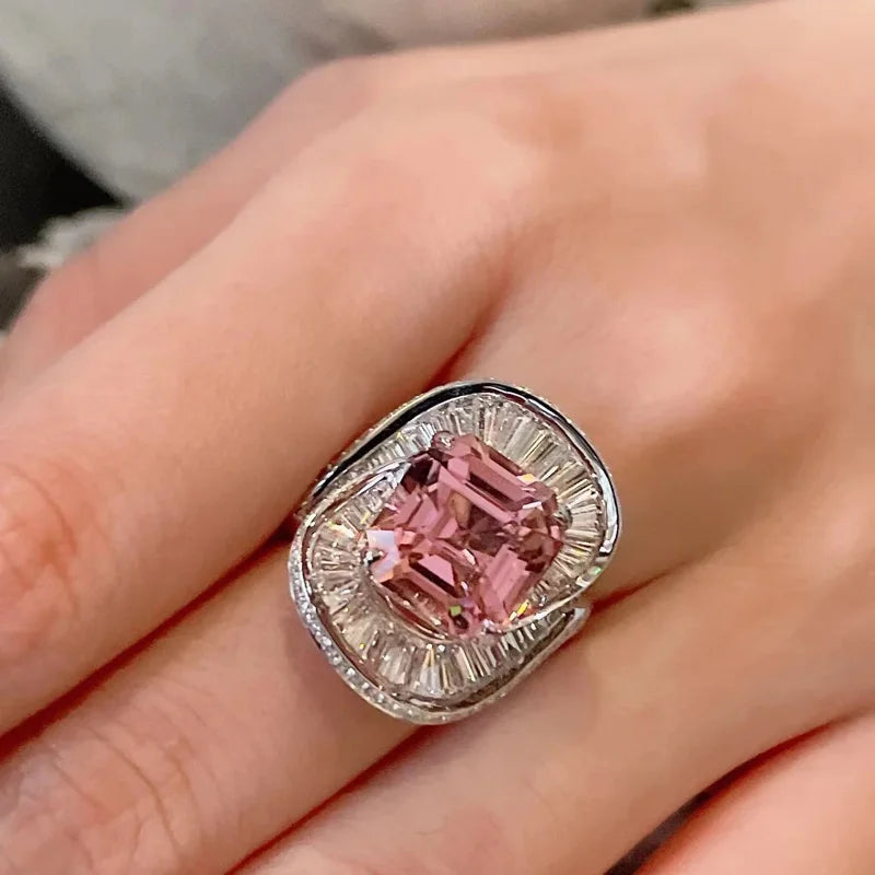 Pink quartz charms and floral wedding rings from Corporación Turística, featuring silver adjustable jewelry with intricate flower designs.