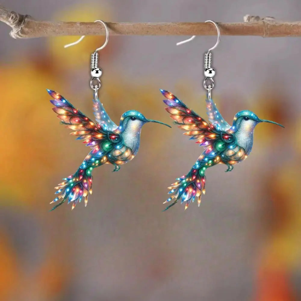 Acrylic hummingbird-shaped earrings featuring vibrant colors and intricate design, stylish jewelry by Corporación Turística.