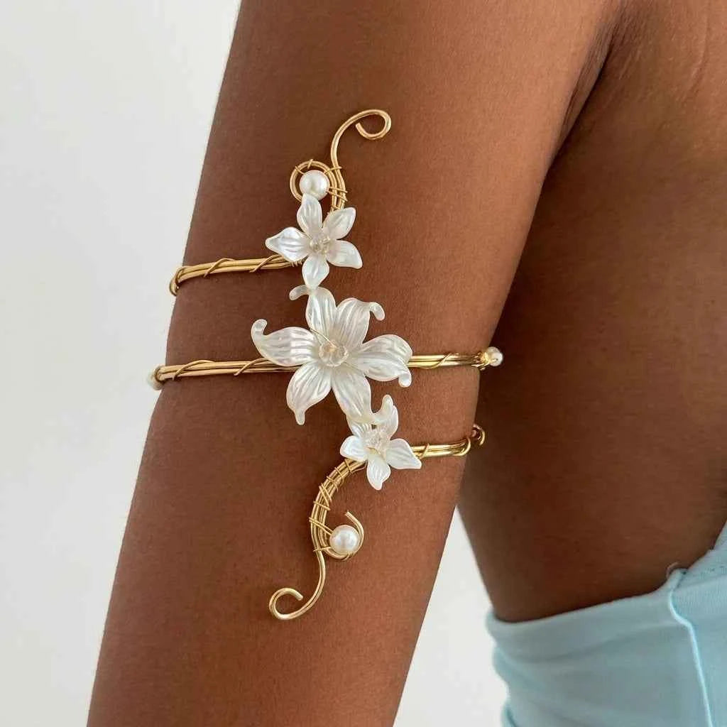 Open bracelet with white floral design in elegant boho style, crafted by Corporación Turística, featuring intricate metalwork and floral accents.