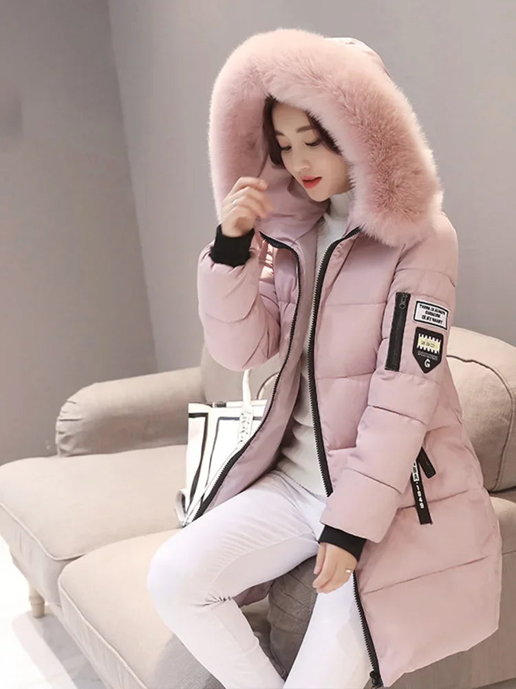 Long black women's winter coat with hood and high collar, designed for warmth and style by Corporación Turística.