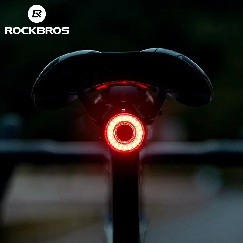 ROCKBROS smart rechargeable bike rear light for nighttime safety, mounted on bicycle, with bright LED illumination.
